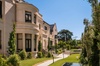 A luxurious villa surrounded by a beautifully landscaped garden under clear blue skies.