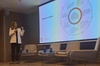 A woman is presenting at a conference with a visual aid explaining best practices for managing projects successfully.