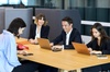 Four business professionals working and discussing around a table in a modern office setting.