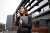 A professional woman holding a briefcase speaks on her phone outside a modern building.