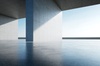 A modern architectural interior with concrete pillars and a view of the sea.