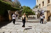 A group of people walking on stone steps in a sunny courtyard.