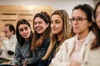 A group of young people sitting in a seminar, smiling and paying attention.
