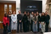 A group of people standing together in a modern office space, with a presentation screen in the background.