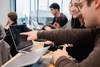A group of students collaborating on a laptop in a classroom setting.