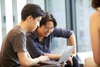 Two people are collaborating on a laptop while sitting together in a modern workspace.