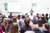 A crowd of people attending a presentation in a lecture hall.