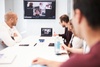 A team meeting conducted via video conference with participants in a modern office setting.