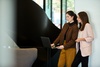 Two women standing and using a laptop together in a modern office setting.