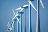 A line of wind turbines against a clear blue sky.