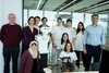 A group of individuals posing with a robot in a modern office setting.