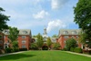 A scenic view of a college campus featuring brick buildings and a clock tower surrounded by greenery.