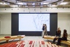 A modern interior space featuring a large digital screen and people interacting.