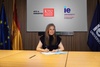 A woman is sitting at a table signing documents in front of logos from King's College London and IE University.