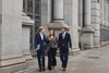 Three young professionals walk together in a stylish urban environment.