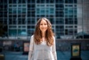 A young woman smiling in front of a modern building