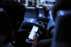 A person using a smartphone on a bus at night, with other passengers visible in the background.