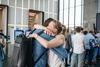 A joyful reunion between two people embracing in a lively environment.