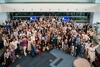A large group of people is gathered together, smiling and posing for a photo.