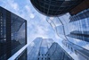 Looking up at a cluster of modern skyscrapers under a clear blue sky.