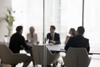 Blurred image of a group of professionals in a meeting around a table in a modern office.