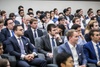 A large group of people dressed in formal suits attending a conference or seminar.