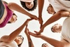 A diverse group of people forming a circle with their hands in a collaborative gesture.