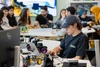 A student is focused on their laptop while various robotics projects are displayed on the table in a classroom setting.