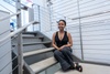 A young woman is sitting on the stairs in a modern indoor space.