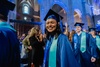 A joyful graduate wearing a blue cap and gown smiling at a ceremony.