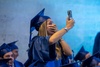 A joyful graduate taking a selfie while celebrating her achievement.