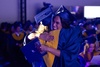 Two graduates embrace each other in celebration at a graduation ceremony.