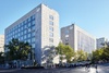 A modern university campus with glass buildings and trees in a clear blue sky.