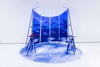 A modern art installation featuring a blue backdrop with mountain imagery and two distinct tables.