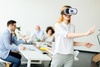 A woman wearing a VR headset is joyfully interacting in a modern office environment.