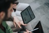 A person is analyzing data on a tablet alongside another individual.