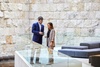 A man and a woman are engaged in conversation in a modern interior space with stone walls.