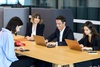 A group of four professionals engaged in a meeting around a table with laptops.