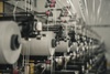 An image showing a row of textile machines spinning yarn in an industrial setting.