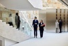 People in a modern corporate building interior, featuring a sleek design with marble and minimalist elements.