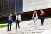 A group of professionals are walking down the steps of a modern building while engaging in conversation.