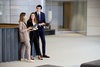 Three professionals engaged in a discussion in a modern office setting.