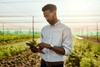 A man using a tablet in a field during sunset.