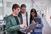 A group of three people collaborating over a laptop in an office setting.