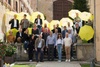 A group of people holding yellow umbrellas posing together on outdoor steps.