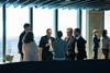 A group of professionals engaged in conversation at a modern office setting with a city view.