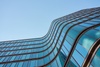 A modern building with wavy glass windows under a clear blue sky.