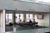 A group of professionals is having a meeting in a modern glass-walled conference room.