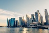 A stunning view of a modern city skyline illuminated by the sun beside a calm water body.