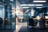 A dimly lit office space with a blurred perspective, featuring an empty chair and illuminated workstations in the background.